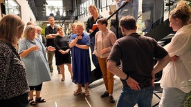 En gruppe mennesker på gulv og trappe samlet om et projekt