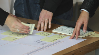 Design thinking Post-its og hænder på et bord med papir