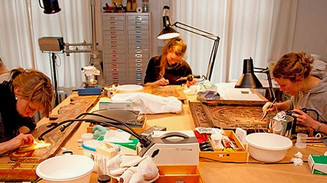 Studerende sidder rundt om bord og arbejder på konserveringsprojekter