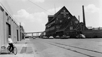 Old photograph of a street a building and a man on a bike