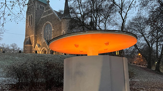 I baggrunden kirke, i forgrunden oplyst karruselstruktur