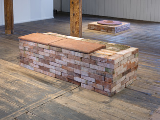 Brick installation in gallery space on wooden floor.