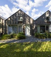  Små træbeklædte huse med private indgange og grønne arealer foran.