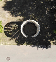 Aerial view of a circular wooden pavilion among large trees.