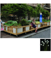 Modular planters with trees and flowers form a green seating area along an urban street.
