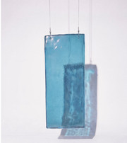 Transparent blue glass panel suspended by thin wires, casting a blue shadow.