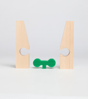Two separated wooden parts with a green connector placed between them.