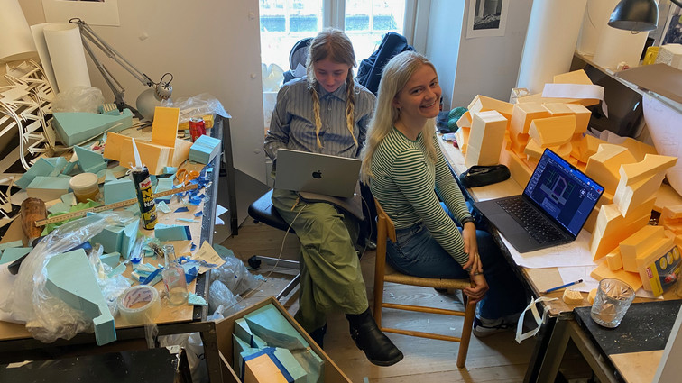To studerende på tegnesal omgivet af modeller og skumrester