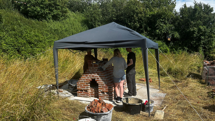 Studerende murer under sort havepavillon