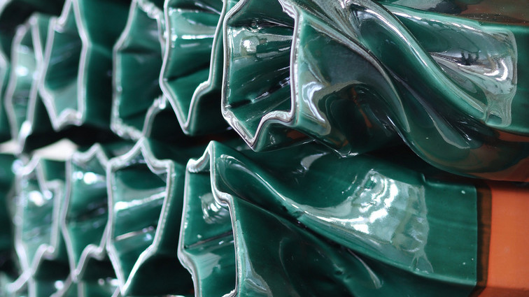 Close-up of glossy, folded green ceramic elements.