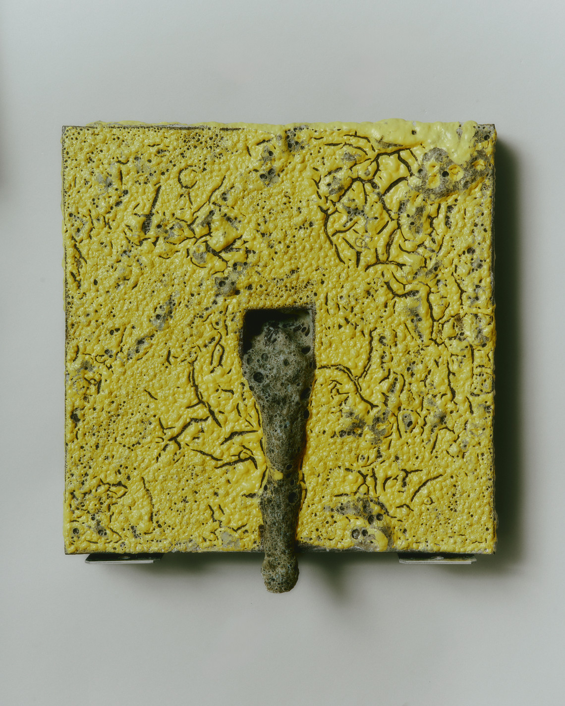 yellow square with grey lava glaze spilling from inside