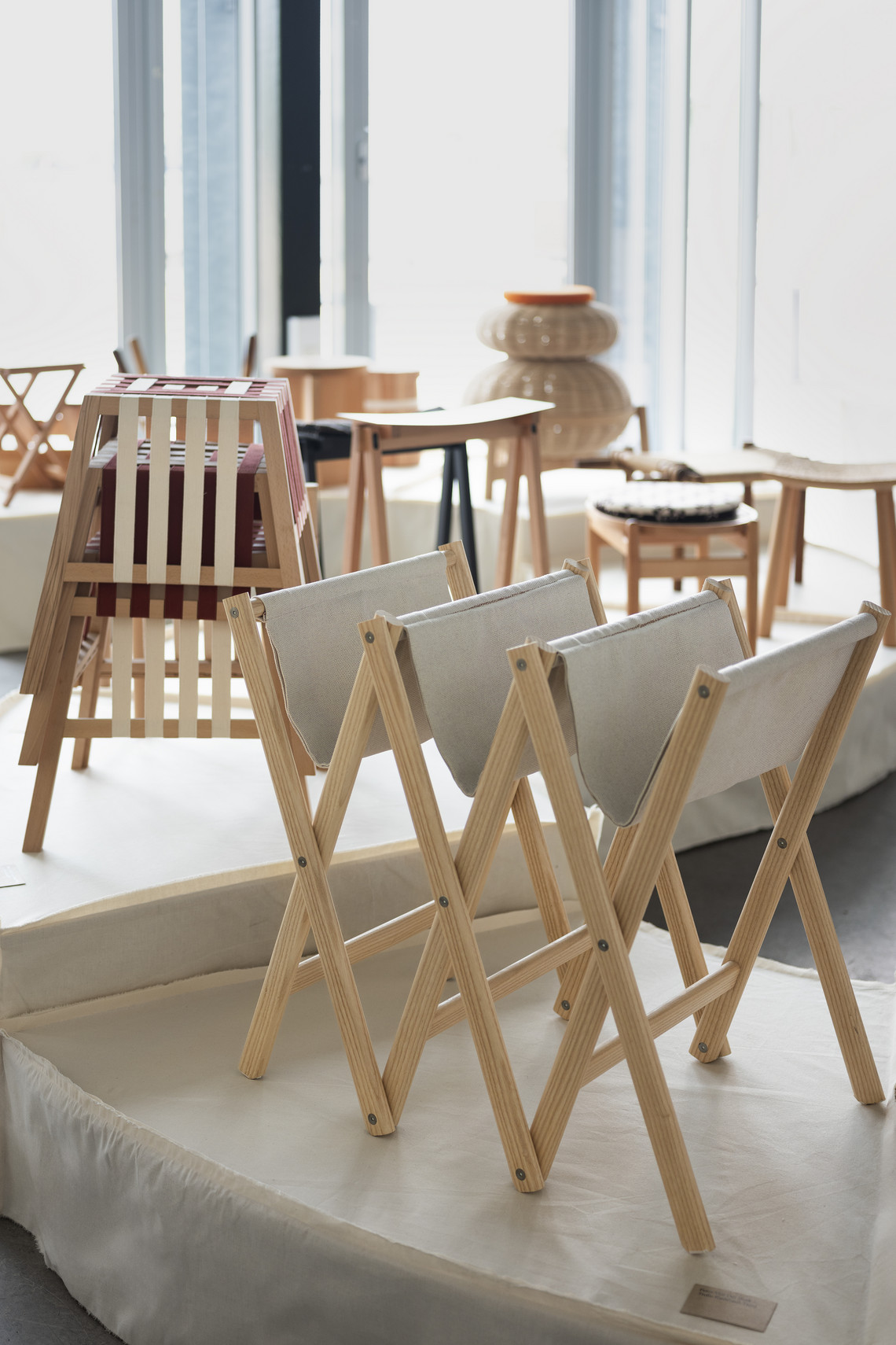 Foldable wooden chairs displayed on an exhibition platform.