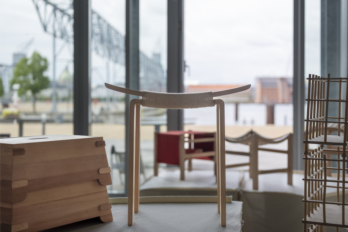 Wooden stool and small furniture pieces by a window.