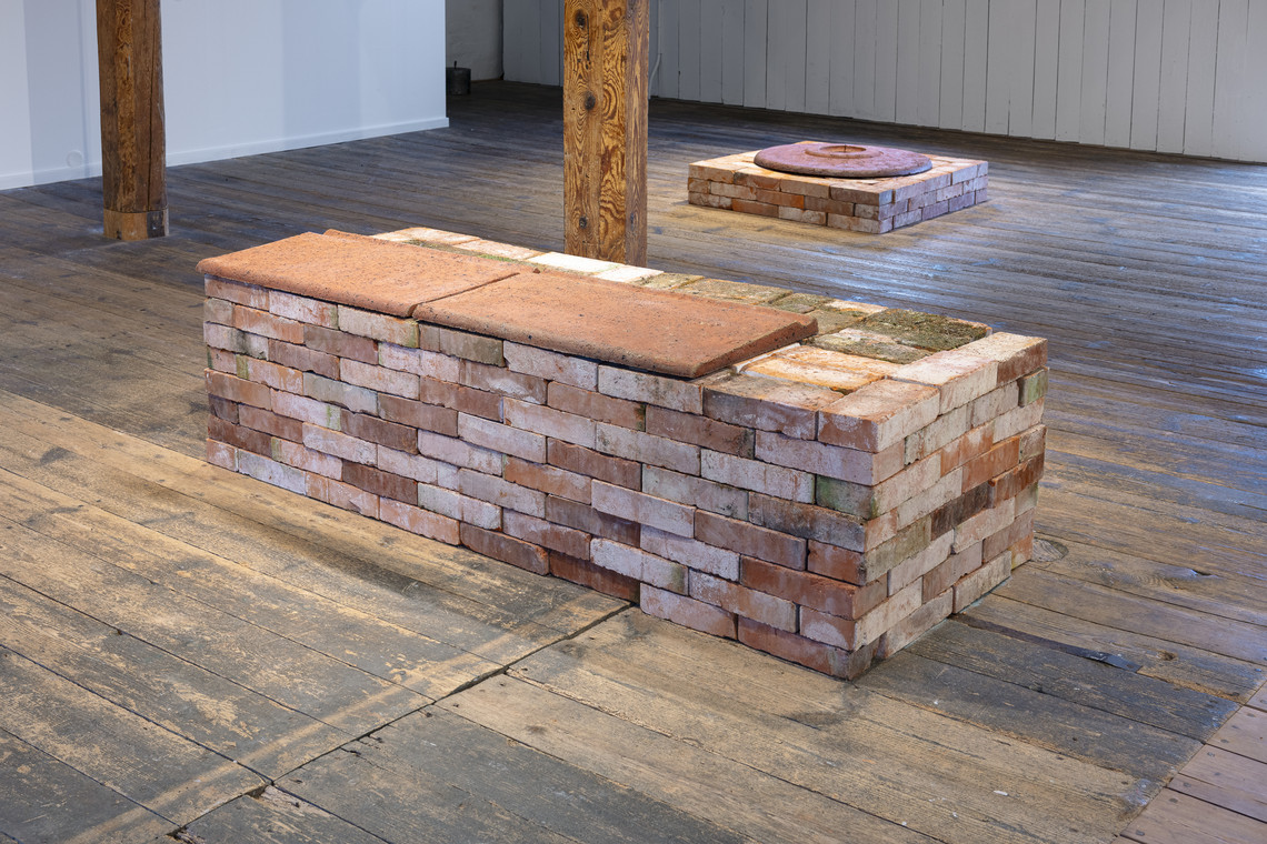 Brick installation in gallery space on wooden floor.