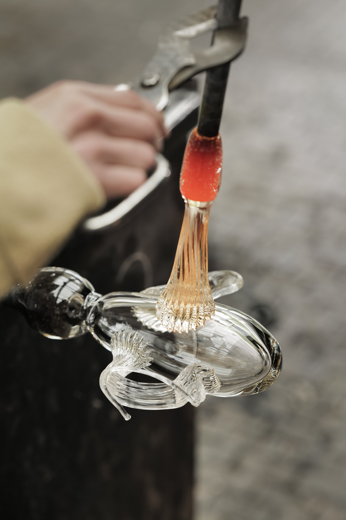 Molten glass being shaped on a rod in a workshop.