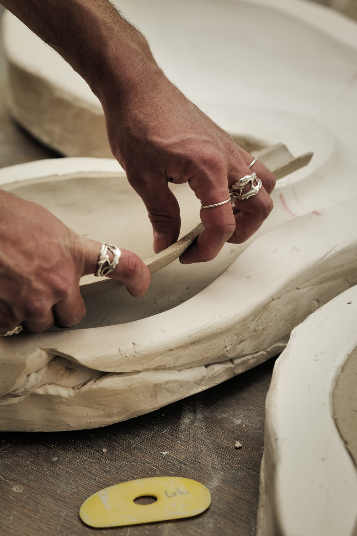 Hands shaping a clay bowl in a workshop.