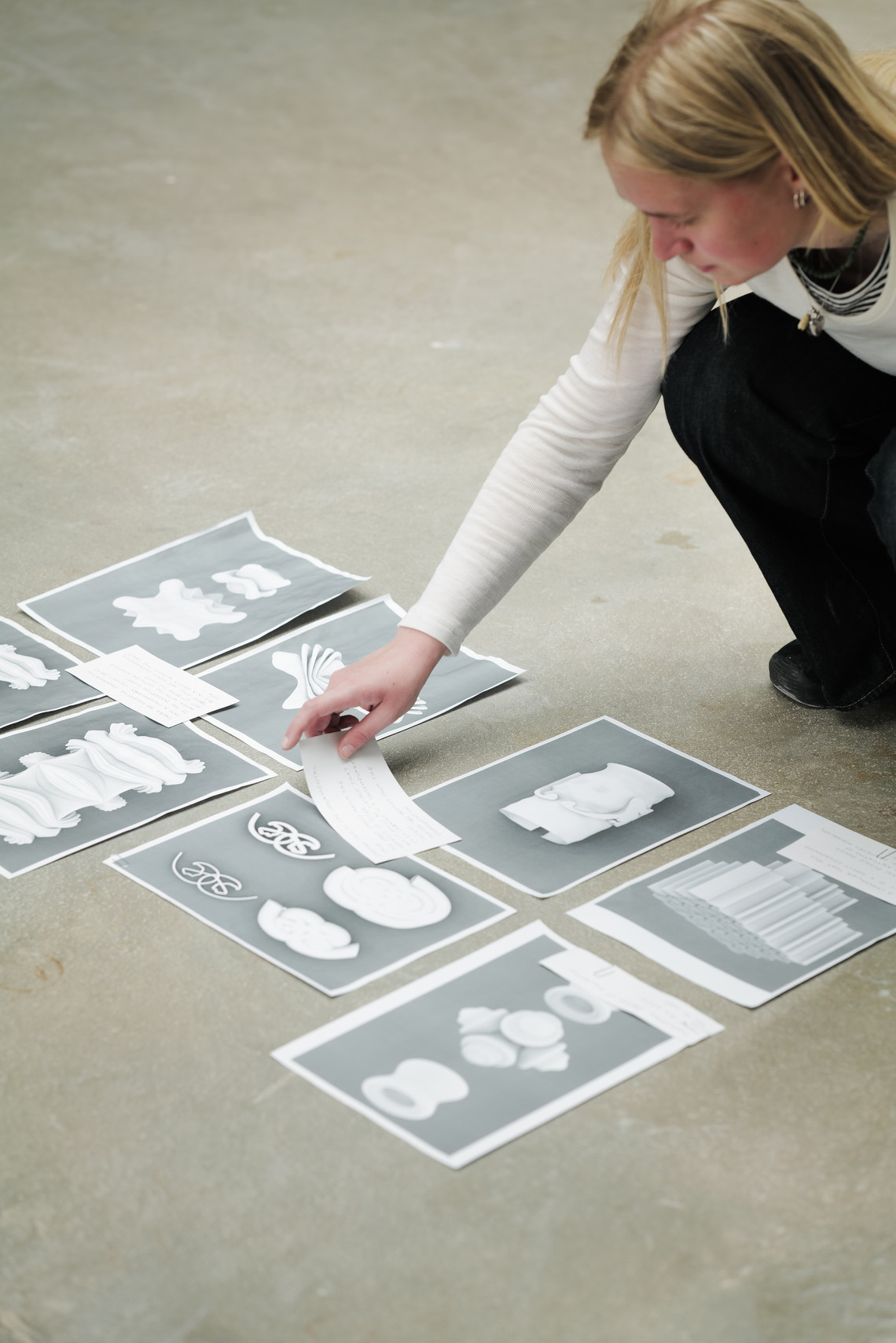 Person arranging printed images of shapes on the floor.