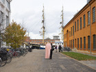 People walking near bicycles and a tall ship.