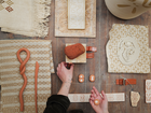Hands arranging clay samples and tools on a worktable.