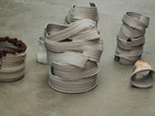 Abstract clay vessels with layered, sculptural surfaces on a floor.
