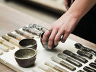 Hand placing ceramic samples and small bowls on a board.