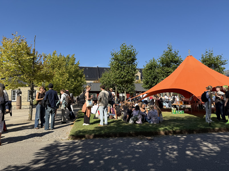 Orange telt, blå himmel, mange mennesker. 