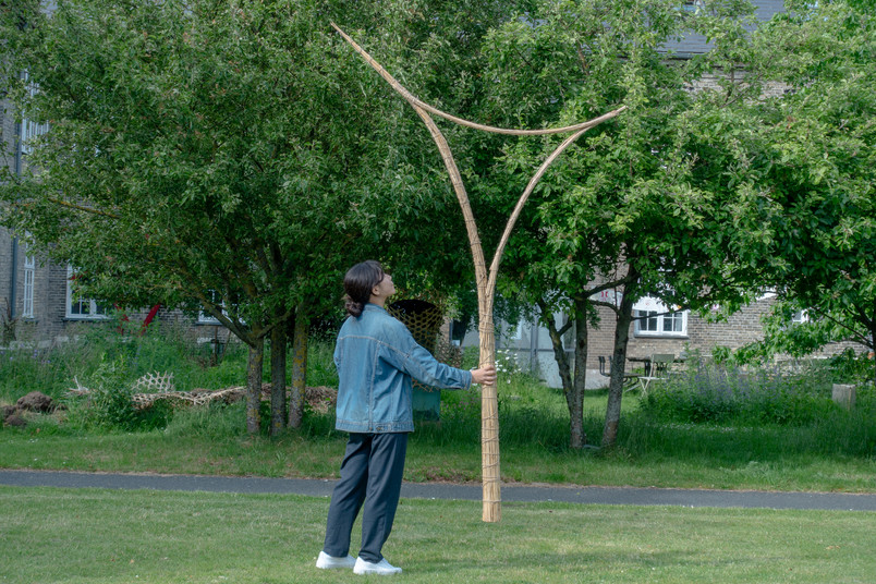 Person holder en oprejst bambusstruktur med to grene.