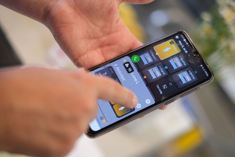 Hånd, der betjener en smartphone med en app‑grænseflade.