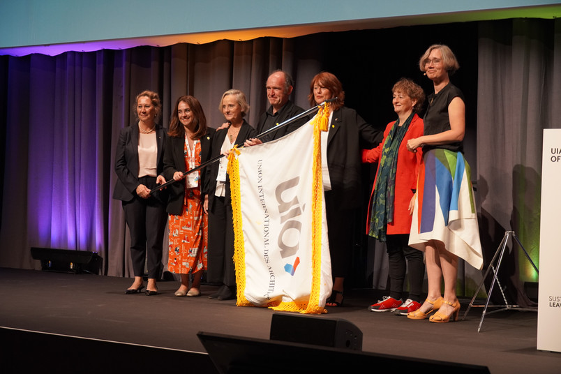 A group of people on stage holding a flag during a formal event at the UIA World Congress of Architects.