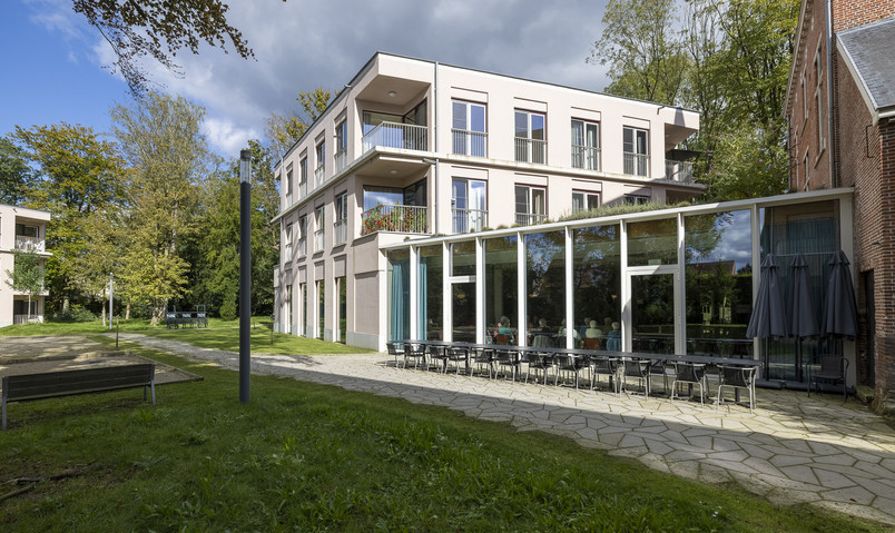 Moderne boligbyggeri med glasfacade og terrasse ved grønne omgivelser