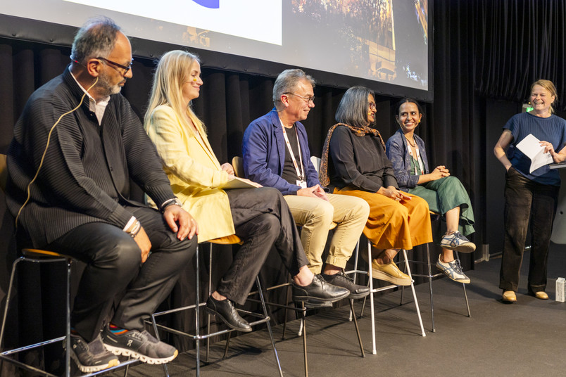 Panel discussion on stage with multiple speakers and a moderator at an architecture congress.