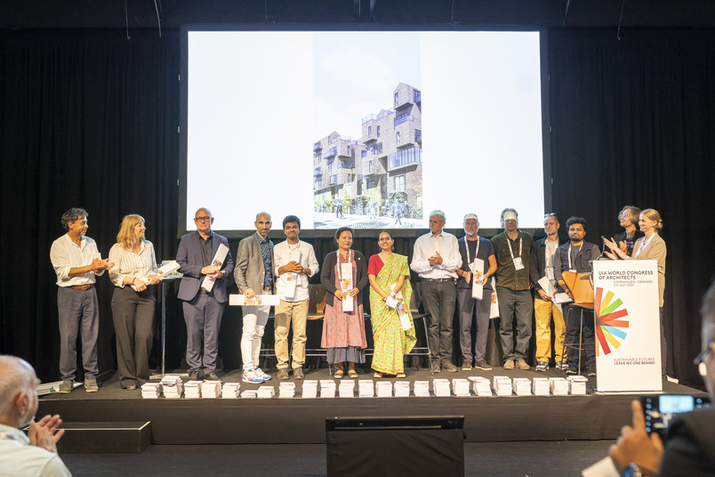 Group of participants on stage holding certificates during an award presentation at the UIA World Congress of Architects.