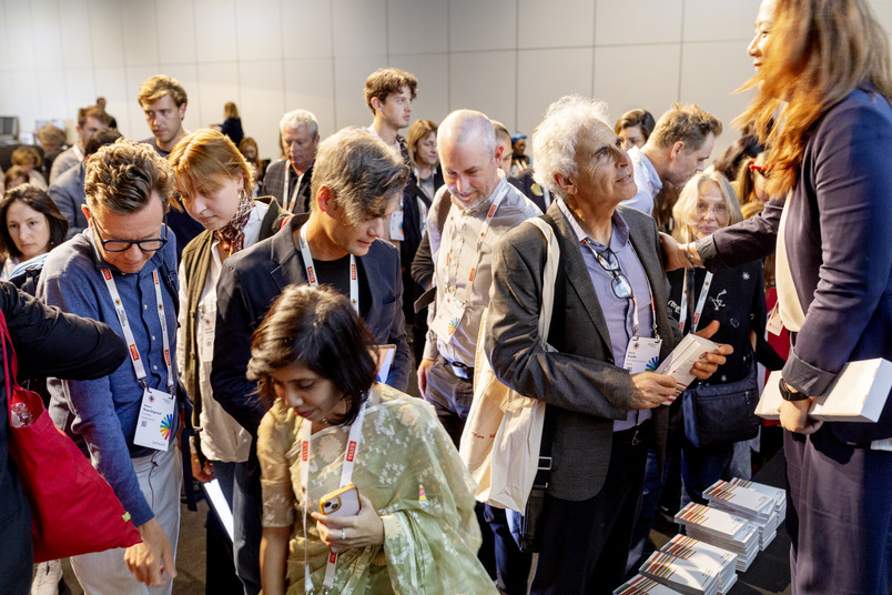 rowd of attendees gathering around a table to pick up books at a conference event.