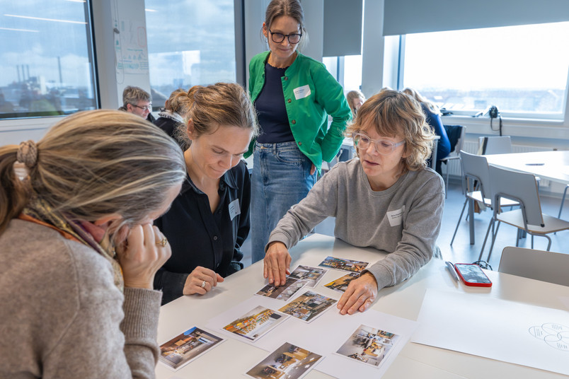 En gruppe gennemgår printede fotos og diskuterer dem ved et bord.