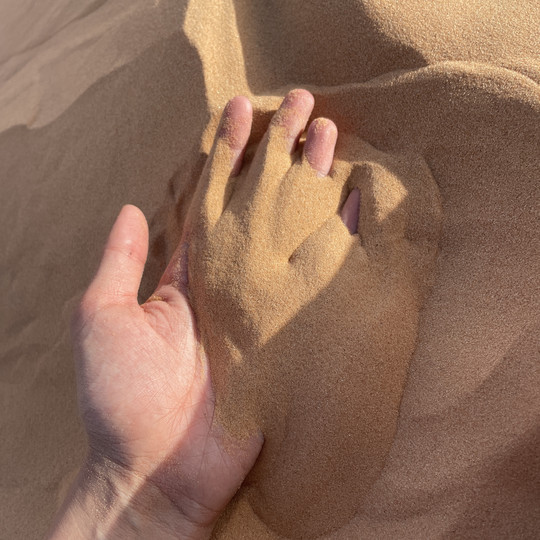 Hand with red sahara sand.