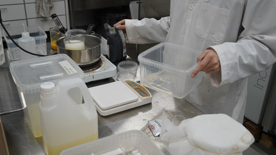 Laboratoriearbejde med vægte, beholdere og væsker på bordet.