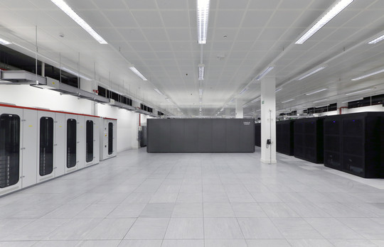 Et stort, hvidt datacenter med serverracks og kabelføring under loftet.