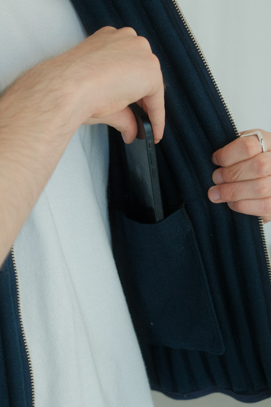 Person lægger en smartphone i en indvendig lomme på vesten.