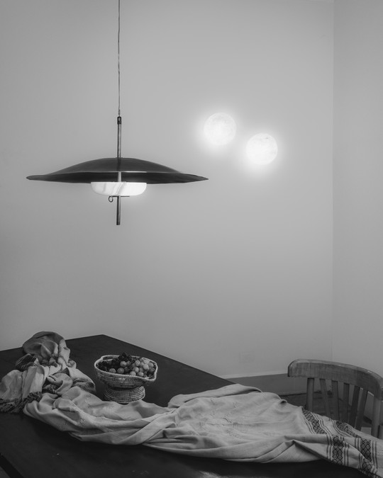 Spisebord med frugtskål og loftslampe, der reflekterer lys på væggen.