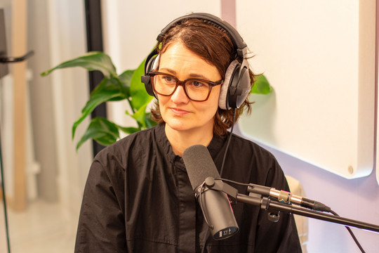 Margrethe Odgaard med hovedtelefoner og mikrofon i podcaststudie.