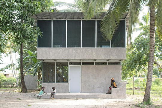 Modern two-story house surrounded by palms and trees, with children and an adult outside.