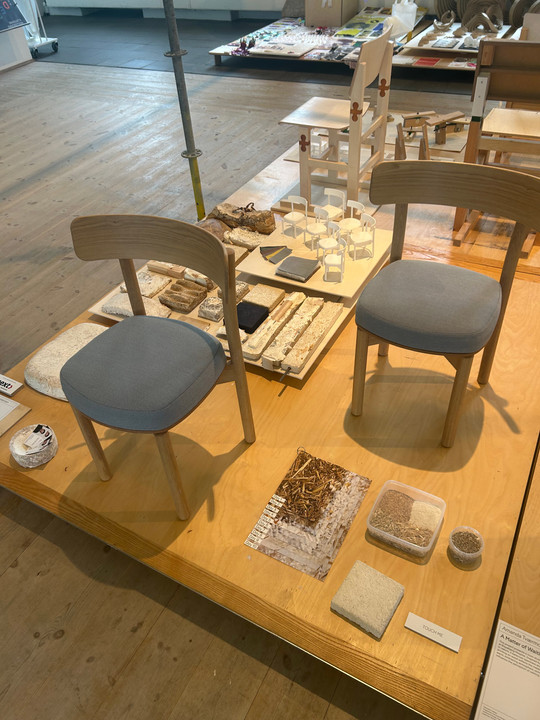 wo wooden chairs with upholstered seats displayed among material samples and chair models.