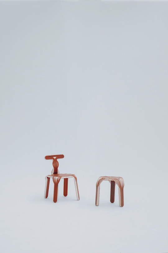 Red chair and stool with organic, layered forms against a light background.