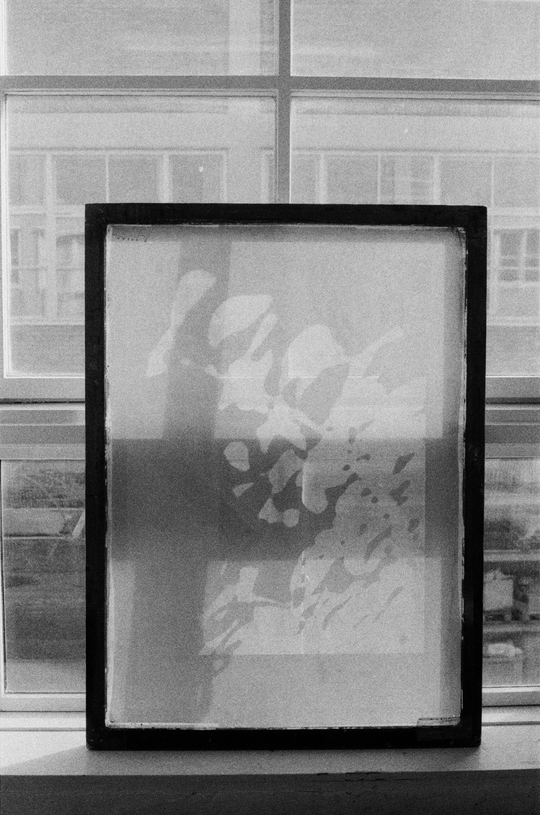 A framed translucent abstract print stands in front of a large window.