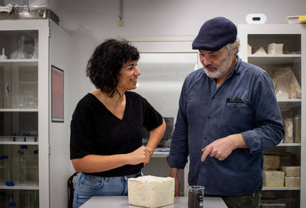To personer undersøger en blok af mycelium på et bord i et laboratoriemiljø