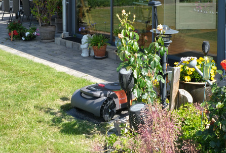 Robotplæneklipper i en have ved et hus.