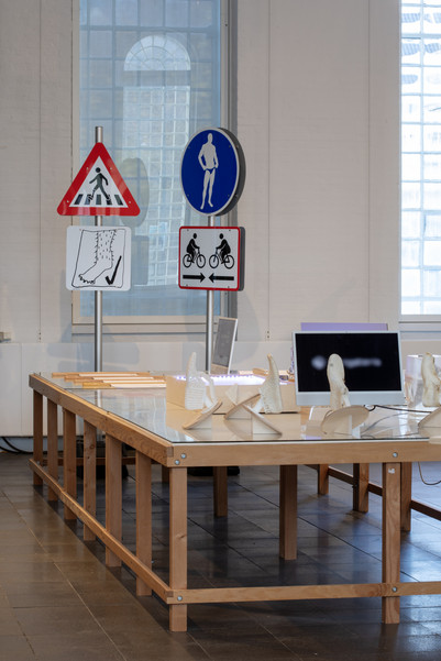 Exhibition with traffic signs, models, and a screen on a large wooden table.