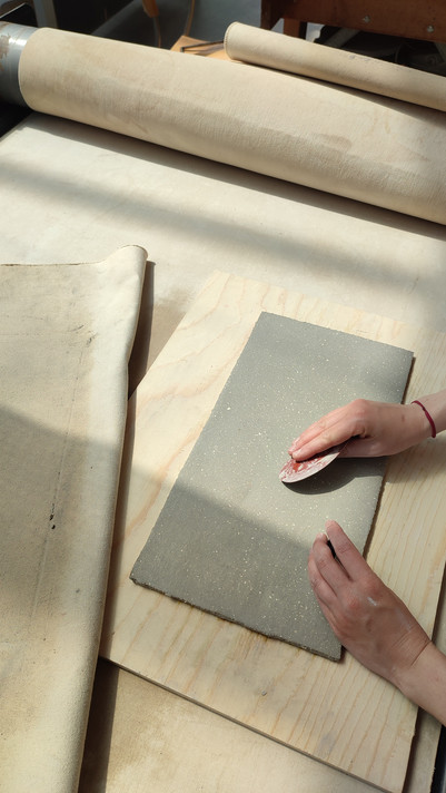 In the workshop, smoothing out the material made from waste. Cladding making process.