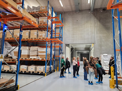 Studerende på museumsmagasin med høje reoler fyldt med kasser