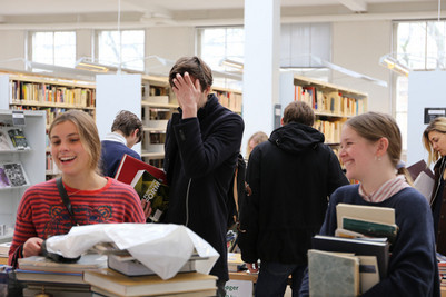 Smilende biblioteksbrugere med favnen fuld af bøger